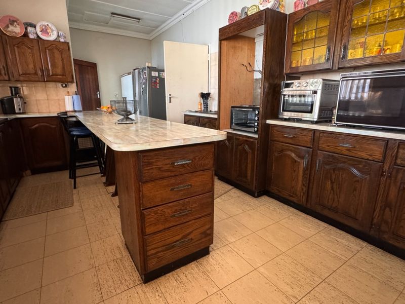A traditional kitchen featuring extensive dark wood cabinetry, a central island with storage, and tiled flooring, offering a functional layout with classic design elements.