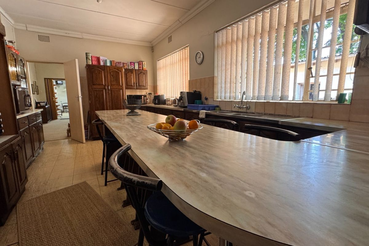 Spacious kitchen featuring extensive laminate countertops, built-in wooden cabinetry, and a double basin sink, offering a functional layout with potential for modern updates.