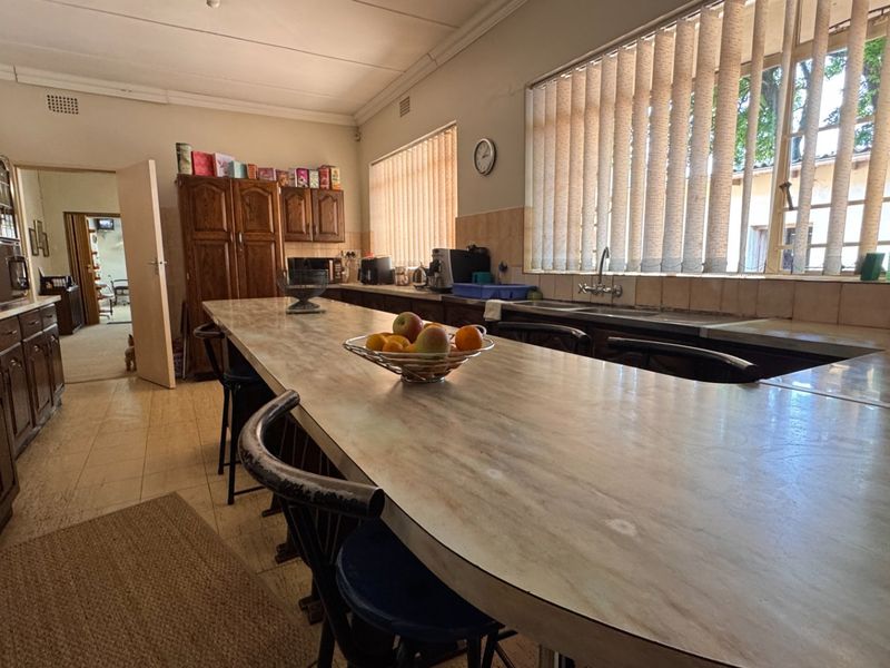 Spacious kitchen featuring extensive laminate countertops, built-in wooden cabinetry, and a double basin sink, offering a functional layout with potential for modern updates.