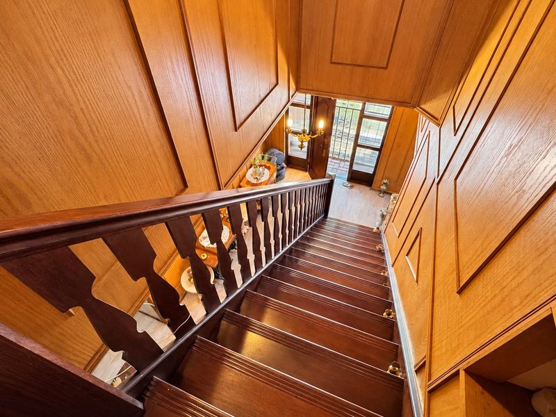 A grand entrance hallway featuring extensive timber wall paneling and a classic wooden staircase leading to the front door.