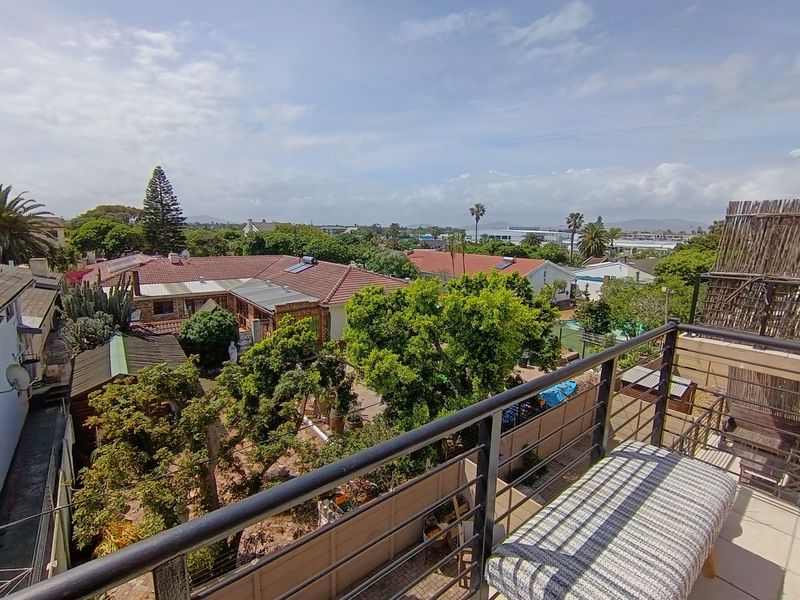 Elevated balcony featuring a metal balustrade and tiled flooring, offering an expansive view over the surrounding residential neighborhood and gardens.
