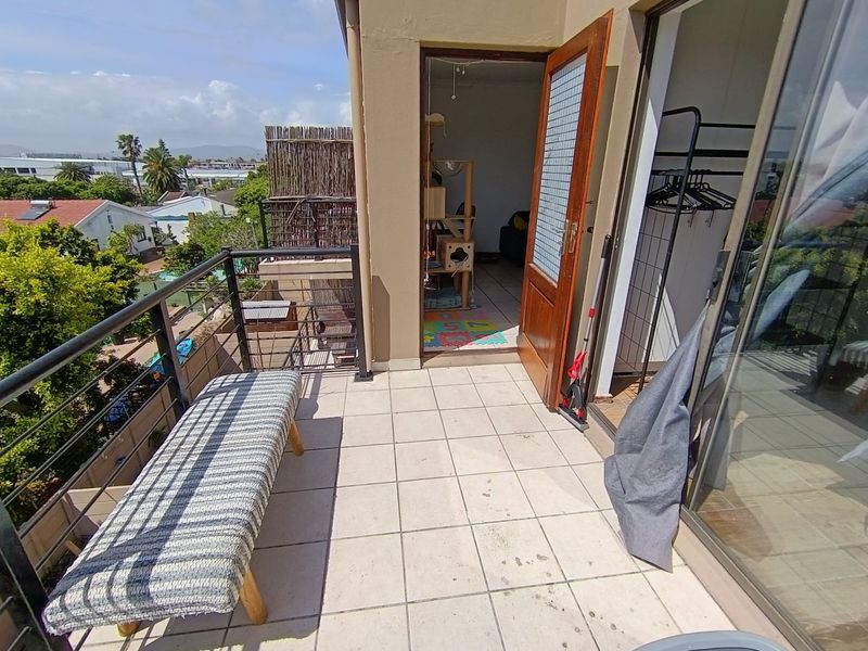 A tiled balcony featuring a metal balustrade and direct access to the interior through a wooden door and sliding glass doors.