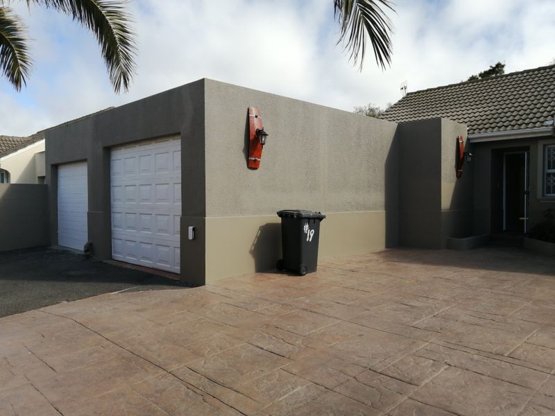 Front view of the property featuring a double garage, stamped concrete driveway, and well-maintained exterior walls with decorative lighting.