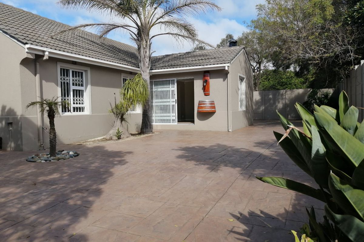 Rear exterior view of the house featuring a stamped concrete patio, secure sliding door access, and a well-maintained perimeter wall.