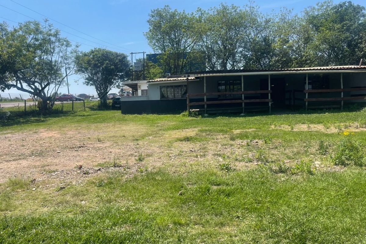 Rear view of a commercial property featuring a covered veranda with timber railing, set on a large grassed lot.