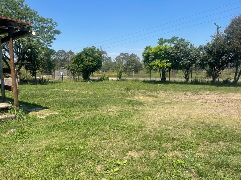 A spacious outdoor garden area featuring a grass lawn, mature trees, and perimeter fencing, offering potential for landscaping or outdoor development.