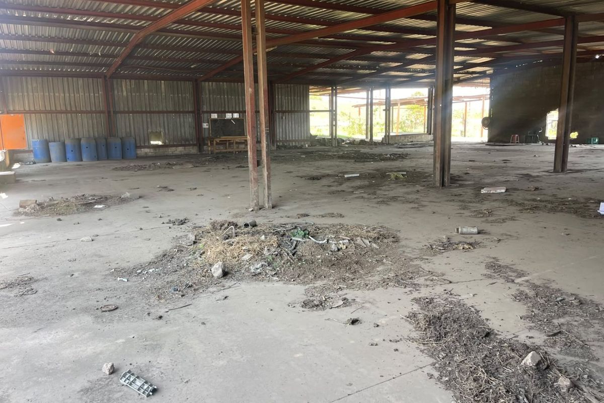 Large open-plan industrial utility space featuring a steel portal frame structure, corrugated metal roofing, and a concrete floor, currently in need of significant maintenance.