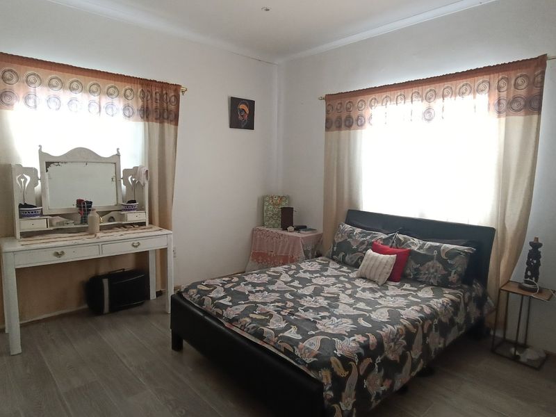 A spacious bedroom featuring laminate flooring and dual windows with natural light, offering a neutral canvas for personalization.