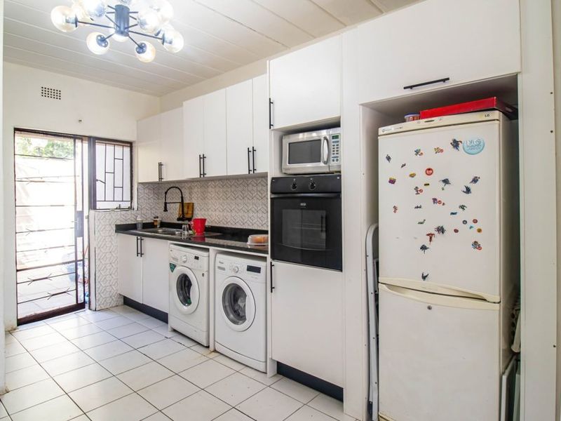 Functional kitchen featuring white cabinetry, black granite countertops, built-in oven and microwave, tiled backsplash, and direct access to an outdoor area.