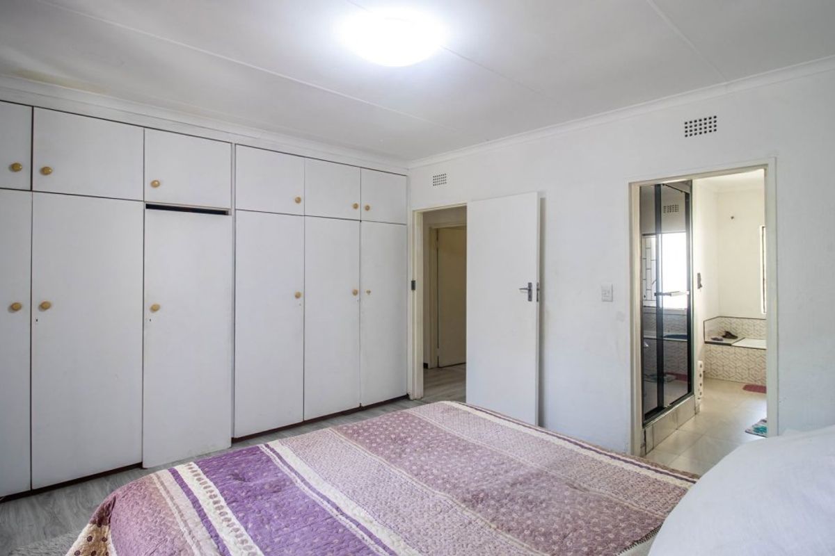 Bedroom featuring extensive built-in floor-to-ceiling cupboards and direct access to an en-suite bathroom.