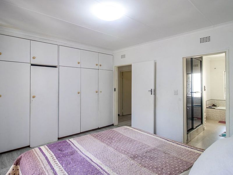 Bedroom featuring extensive built-in floor-to-ceiling cupboards and direct access to an en-suite bathroom.