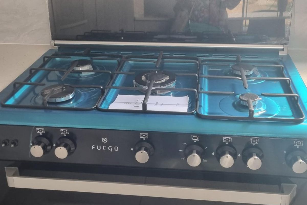 A modern, clean Fuego gas stove and oven unit with a glass splashback and integrated extractor hood.