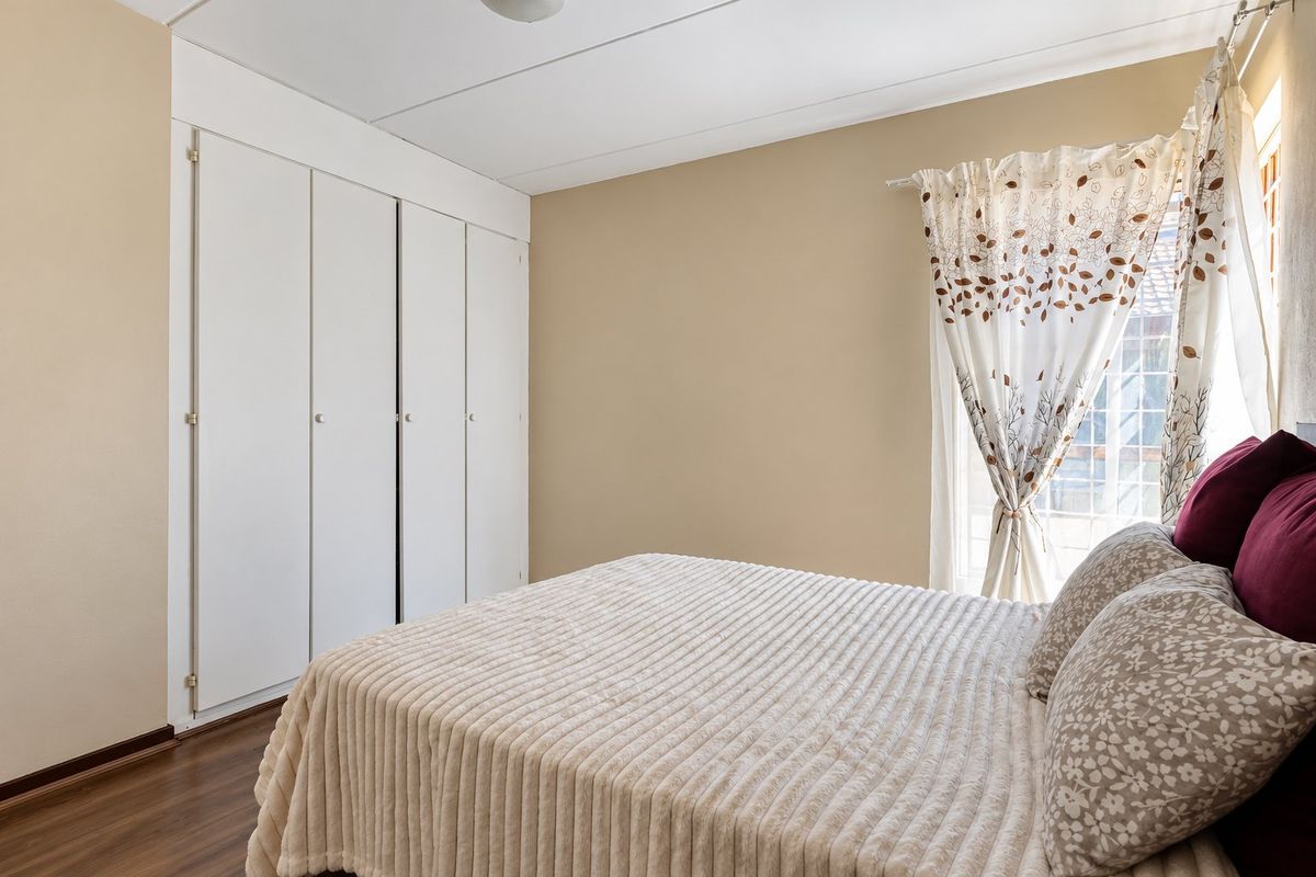 A bedroom featuring laminate flooring, neutral wall tones, and built-in cupboards providing ample storage space.