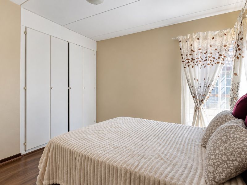 A bedroom featuring laminate flooring, neutral wall tones, and built-in cupboards providing ample storage space.