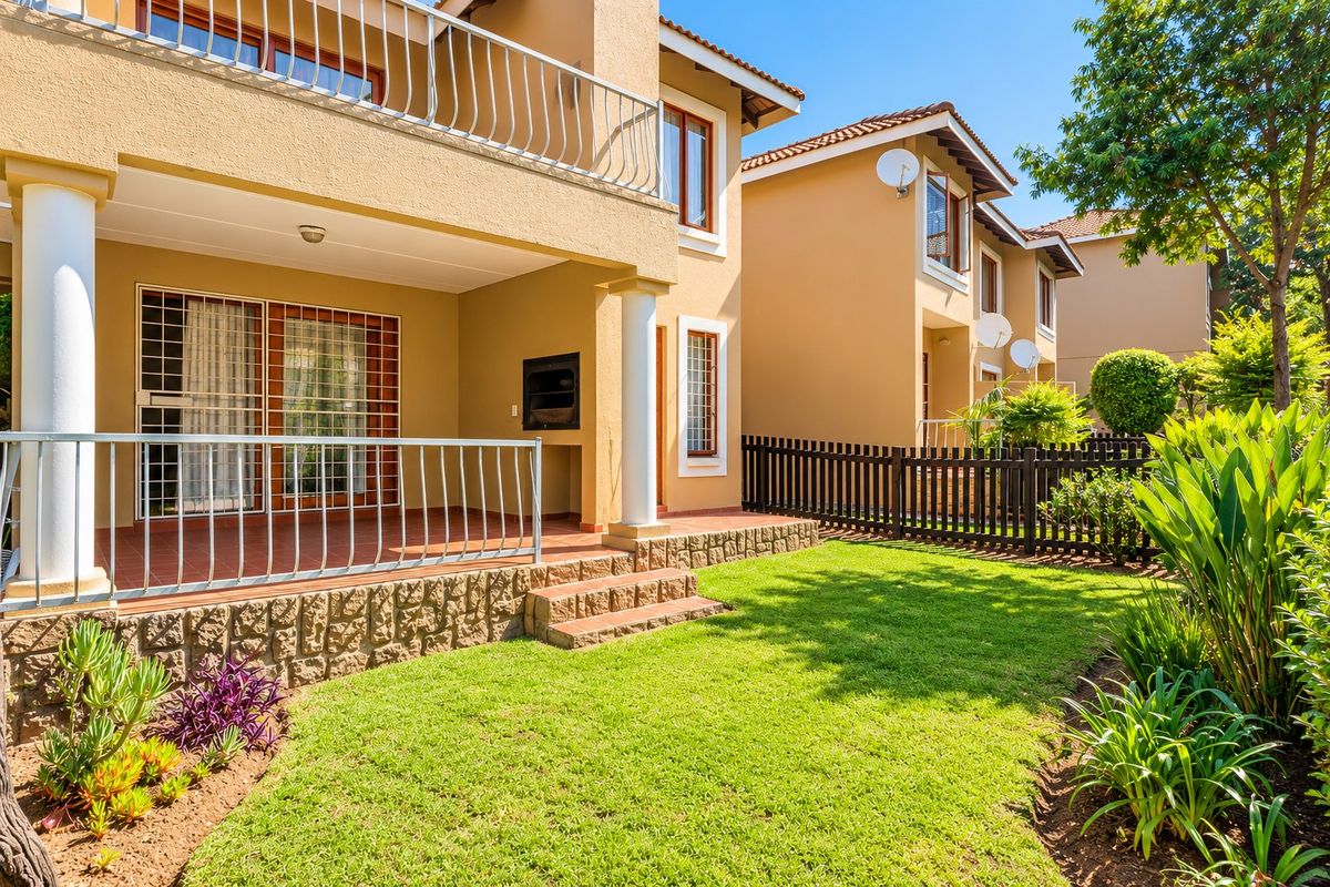 A well-maintained rear exterior featuring a covered patio with a built-in braai, stone-clad steps, and a private garden area.