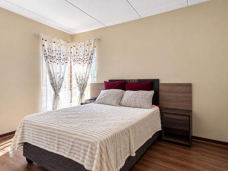 A well-lit bedroom featuring laminate flooring and a built-in headboard with integrated bedside storage.