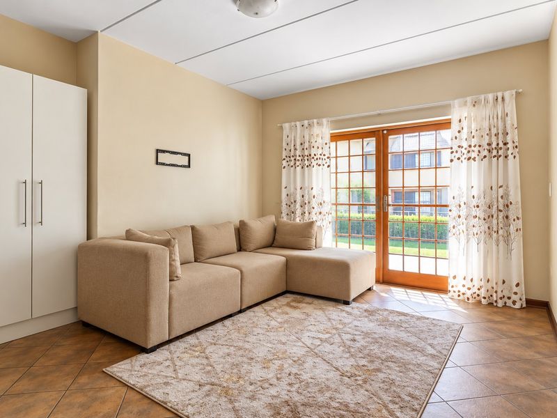 A living room featuring tiled flooring, a built-in wardrobe, and wooden french doors providing access to the exterior.