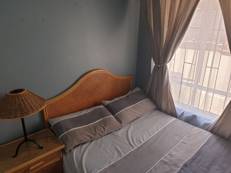 A cozy bedroom featuring a window with security bars and neutral wall tones, offering a functional space for rest.