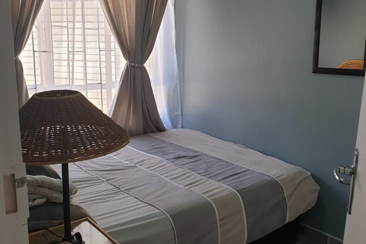 A compact bedroom featuring tiled flooring and a window fitted with security bars, offering a functional and private sleeping space.