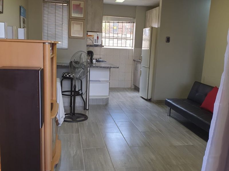 Open plan living and kitchen area featuring tiled flooring, timber ceiling, and functional kitchen cabinetry with granite countertops.