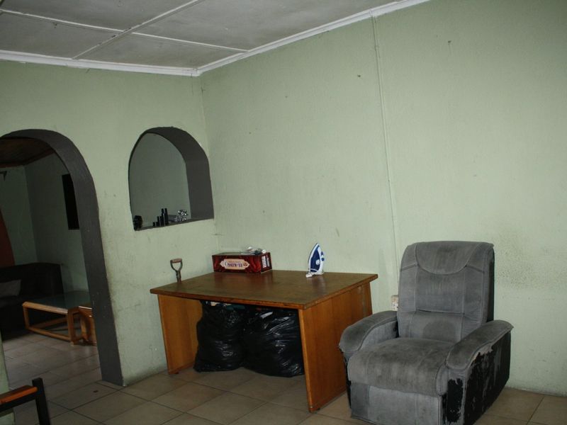 Living area featuring tiled flooring, an arched doorway, and a built-in wall niche, requiring cosmetic updates to improve the overall aesthetic.