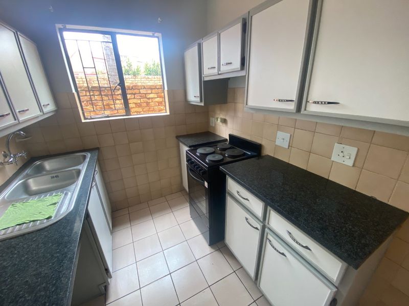Functional kitchen featuring granite countertops, double bowl sink, tiled splashbacks, and ample cabinetry, providing a practical workspace with a window for natural light.