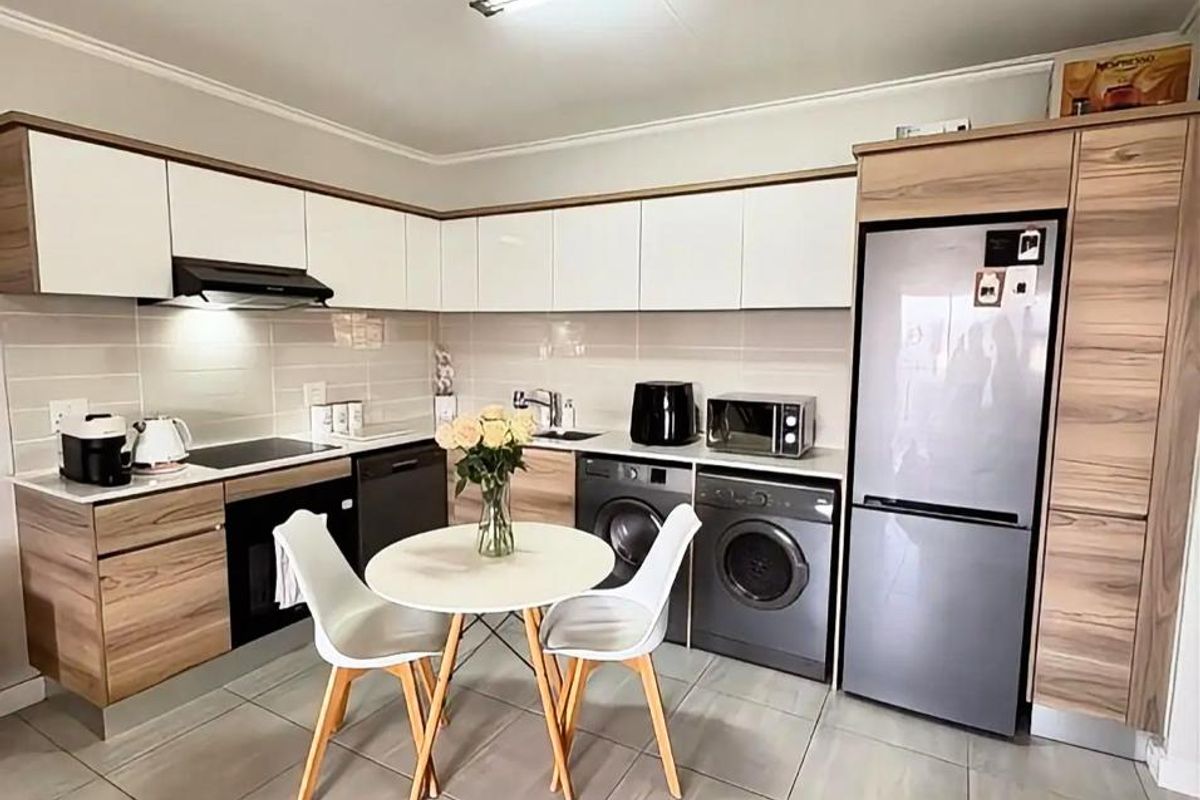 Modern kitchen featuring two-tone wood and white cabinetry, integrated appliances, tiled flooring, and a functional layout with ample storage space.