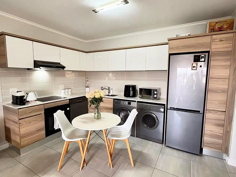 Modern kitchen featuring two-tone wood and white cabinetry, integrated appliances, tiled flooring, and a functional layout with ample storage space.