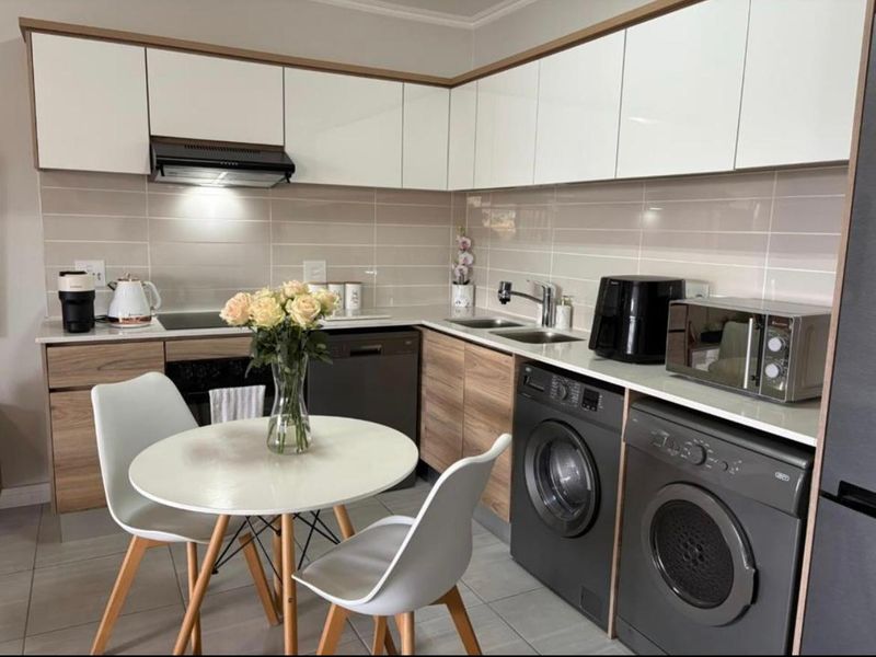 Modern kitchen featuring sleek white and wood-grain cabinetry, tiled backsplash, integrated appliances, and durable tiled flooring in a functional layout.
