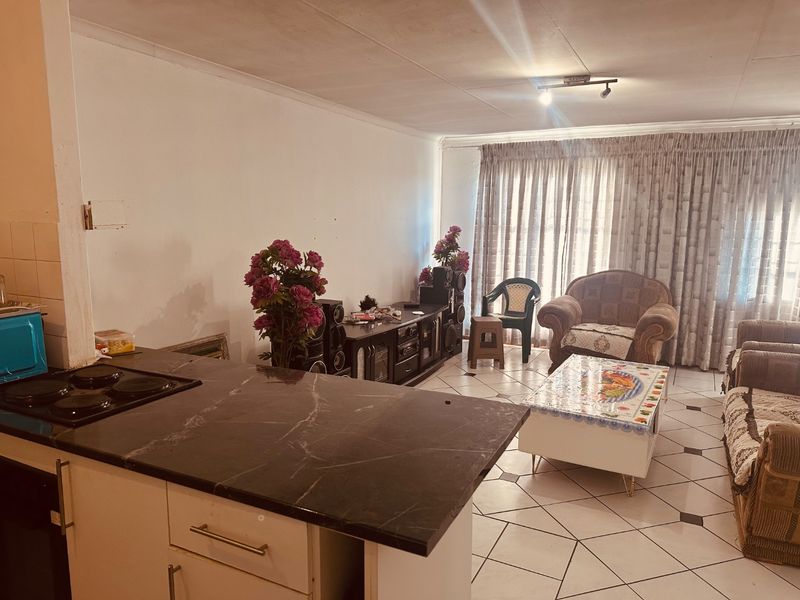 Open plan living and kitchen area featuring tiled flooring, built-in kitchen cabinetry, and a breakfast counter, offering a functional layout for modern living.