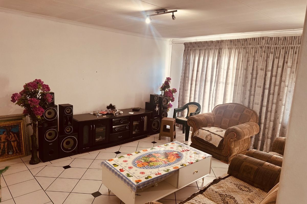 A living room featuring tiled flooring and ceiling track lighting, offering a functional space ready for modern updates.