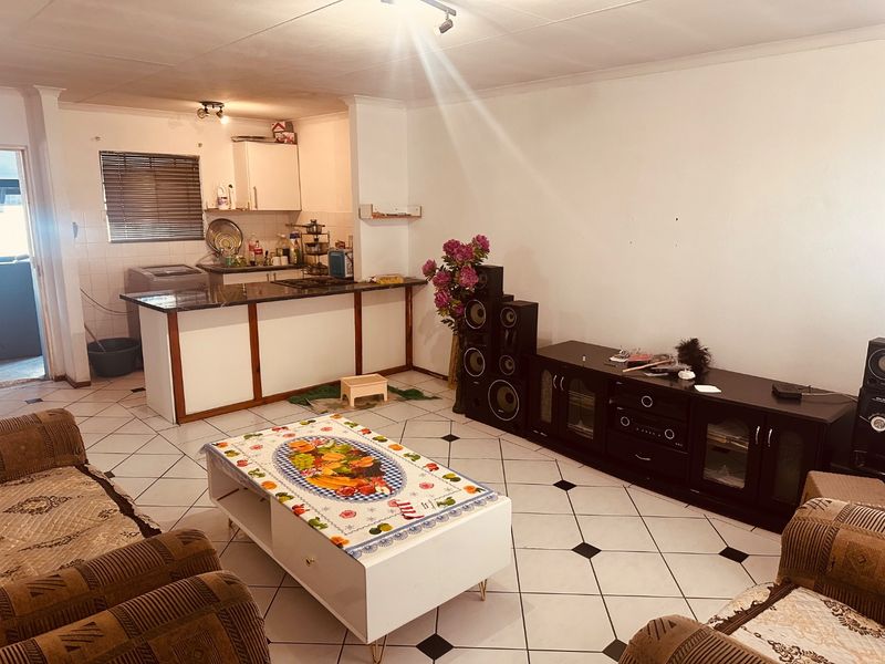 Open-plan living and kitchen area featuring ceramic tiled flooring, a kitchen island with granite countertops, and functional built-in cabinetry.