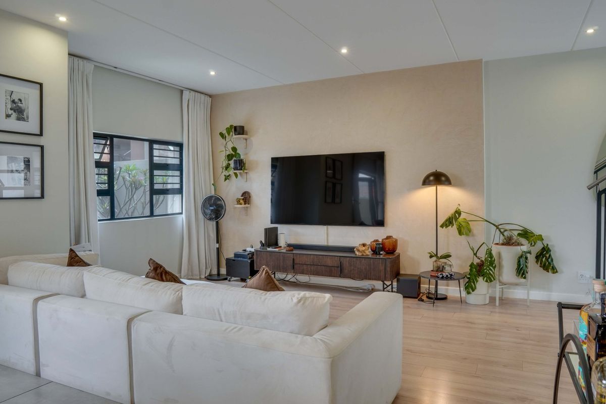 A well-maintained living room featuring laminate flooring, recessed downlighting, and a textured feature wall with integrated television mounting.