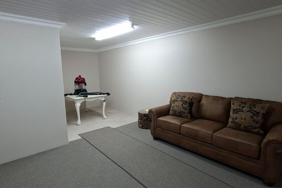 A living room featuring a tongue and groove ceiling, cove cornice, and neutral wall finishes, providing a clean and functional space.