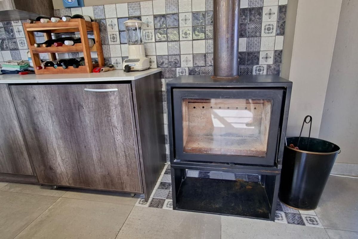 Kitchen area featuring wood-look cabinetry, tiled backsplash, and a built-in fireplace, offering a functional and cozy cooking and living space.