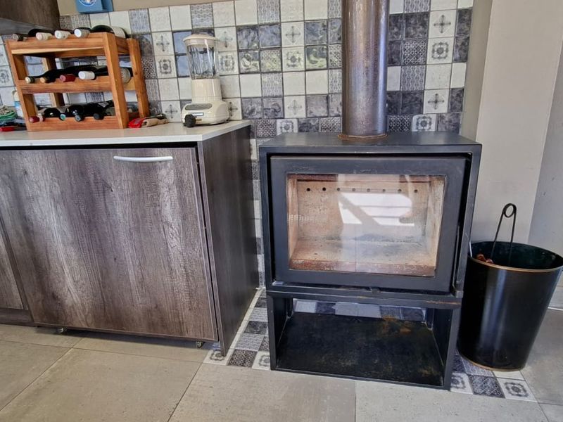 Kitchen area featuring wood-look cabinetry, tiled backsplash, and a built-in fireplace, offering a functional and cozy cooking and living space.
