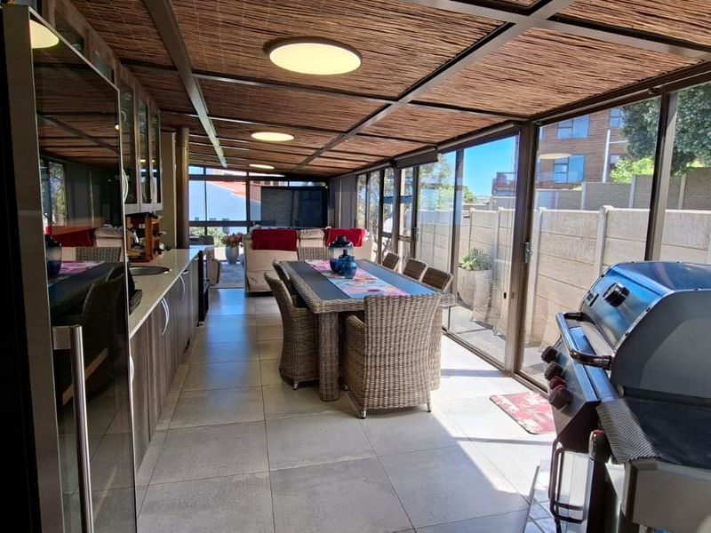 Enclosed patio area featuring tiled flooring, built-in cabinetry, and a thatched roof, providing a versatile space for outdoor dining and entertainment.