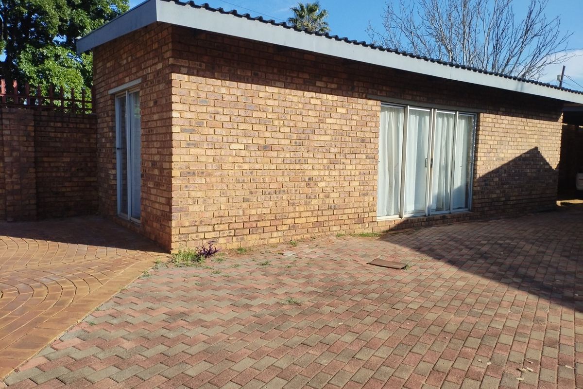 A view of the rear exterior featuring face brick construction, paved outdoor area, and sliding glass door access.