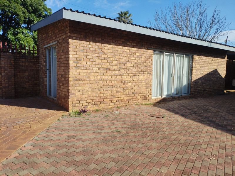 A view of the rear exterior featuring face brick construction, paved outdoor area, and sliding glass door access.