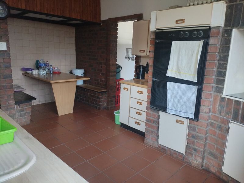 A dated kitchen featuring exposed brick walls, tiled flooring, and built-in cabinetry with an integrated oven.
