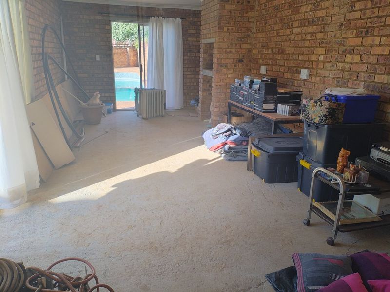 An enclosed patio area featuring exposed brick walls, a built-in brick fireplace, and direct access to the pool area through sliding glass doors.