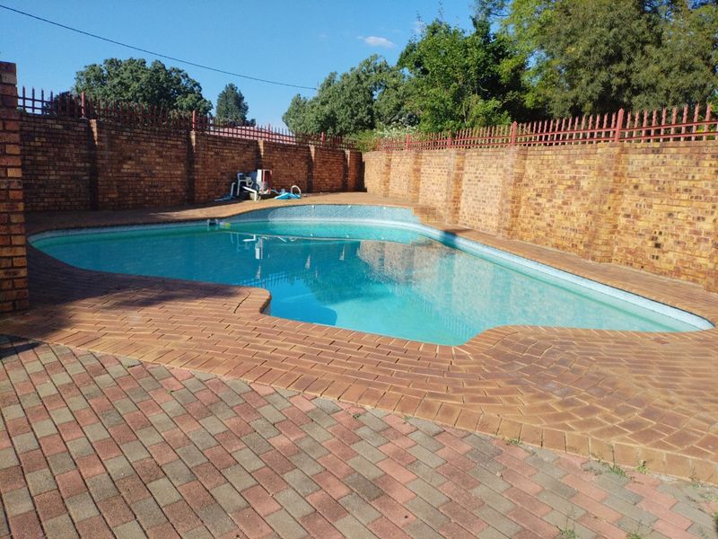 A private outdoor swimming pool area featuring brick paving and secure perimeter walling with metal fencing.