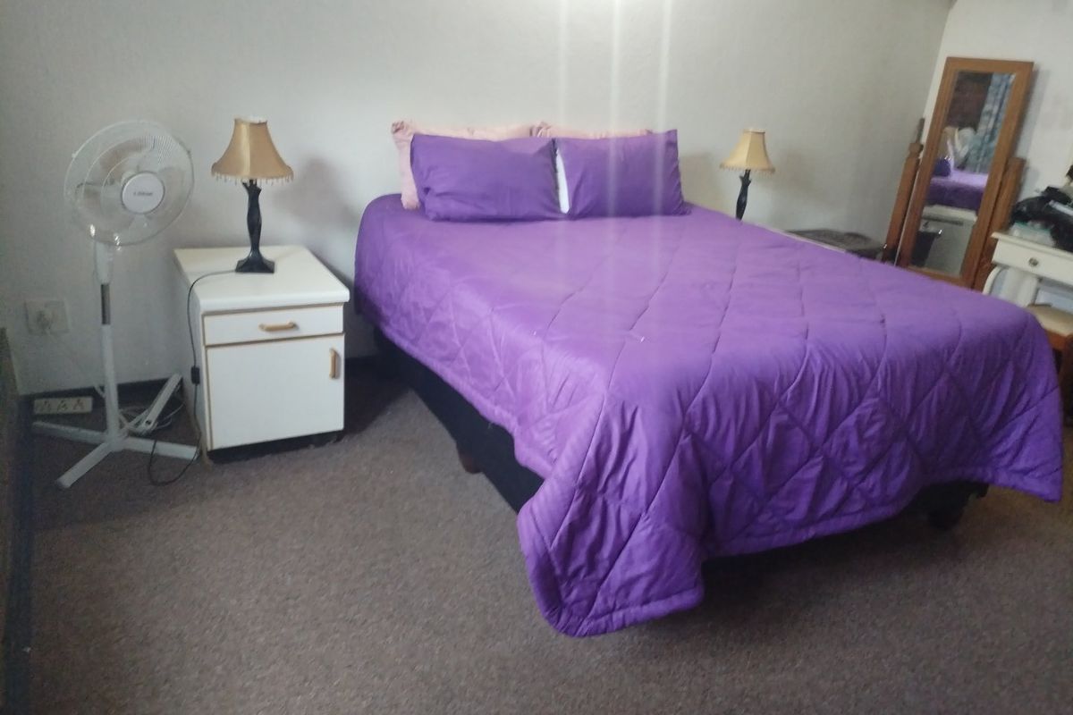 A simple bedroom featuring carpeted flooring and standard electrical fixtures, providing a functional space for rest.