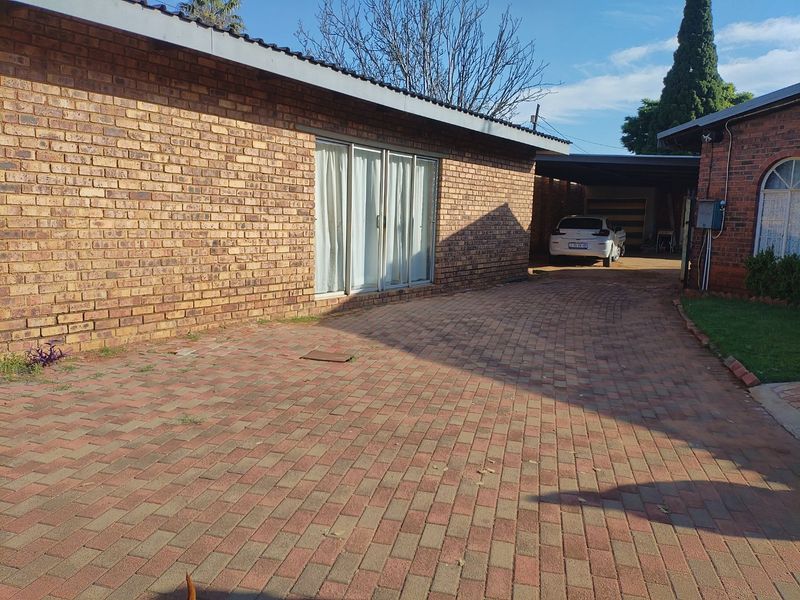 A view of the front exterior featuring a face brick facade, a paved driveway, and a covered carport area.