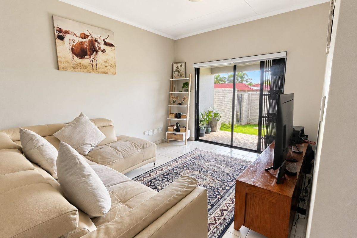 A bright living room featuring tiled flooring and a large sliding glass door that provides direct access to the outdoor patio area.