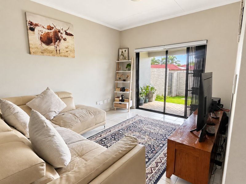 A bright living room featuring tiled flooring and a large sliding glass door that provides direct access to the outdoor patio area.
