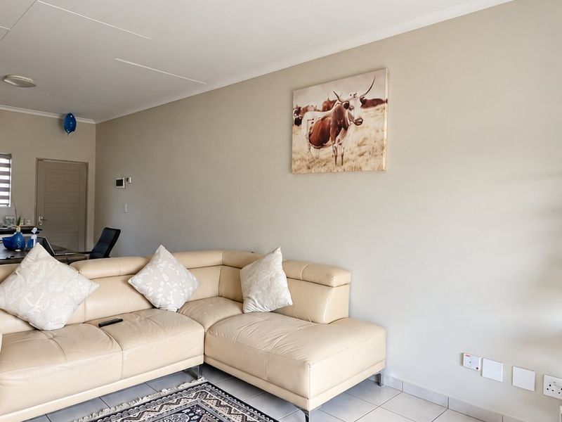 A living room area featuring neutral wall tones, tiled flooring, and integrated electrical points, providing a functional space for relaxation.