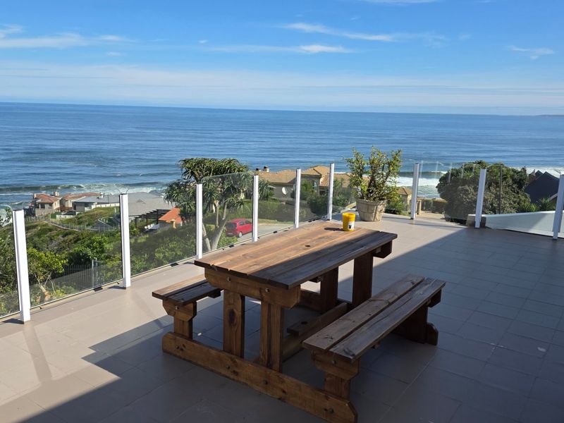 Spacious outdoor balcony featuring a glass balustrade and tiled flooring, offering expansive ocean views.