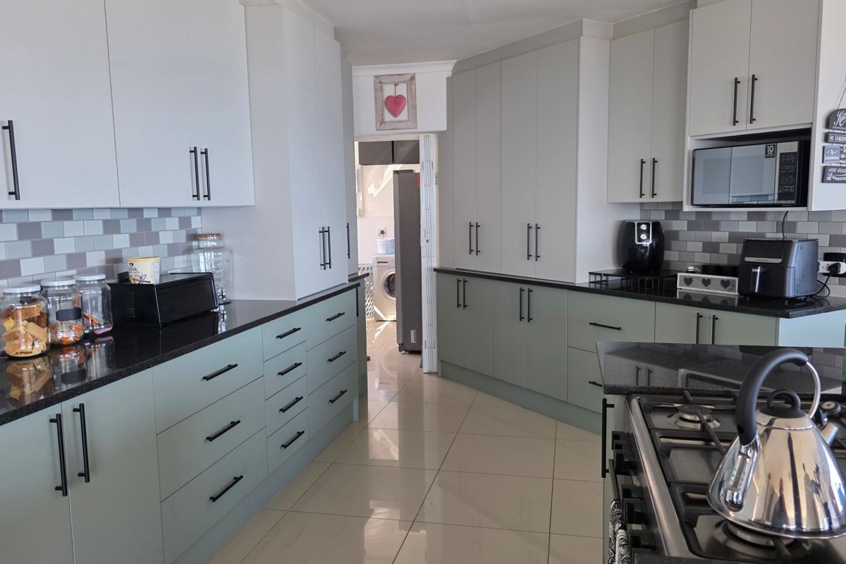 Modern kitchen featuring sage green and white cabinetry, black granite countertops, subway tile backsplash, and integrated gas hob with built-in microwave.