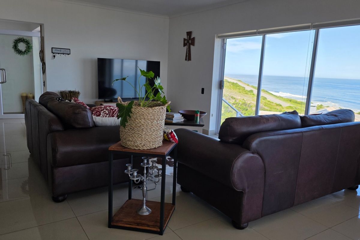 Spacious living room featuring large sliding glass doors that offer expansive ocean views and provide abundant natural light.